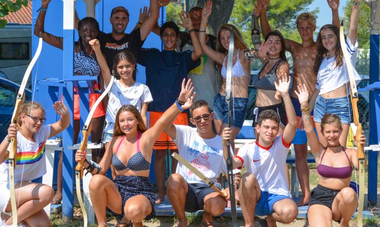 Gruppo di giovani con archi, sorridenti all'aperto.