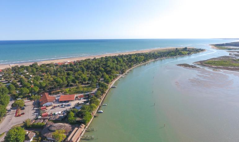Spiaggia e fiume, paesaggio naturale con alberi e case.