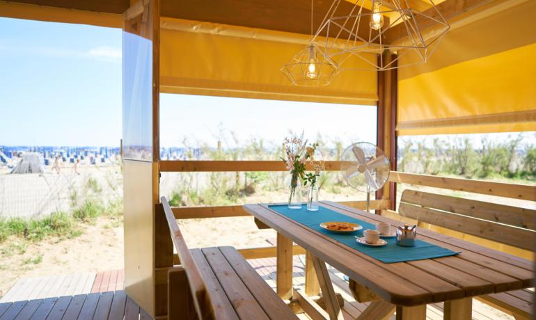 Strand ontspanningsruimte met houten tafel en uitzicht op zee.