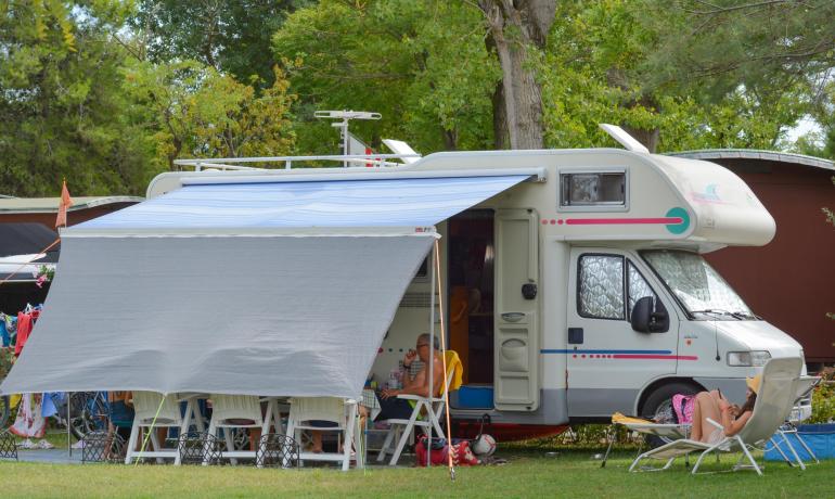 Camper con veranda, persone rilassate all'aperto.