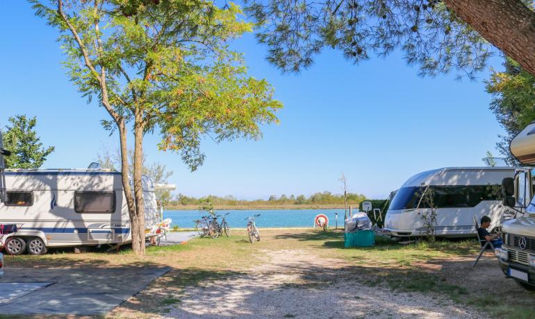 Campeggio con roulotte vicino al lago, biciclette parcheggiate.