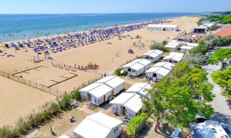 Drukke strand met parasols en bungalows bij de zee.