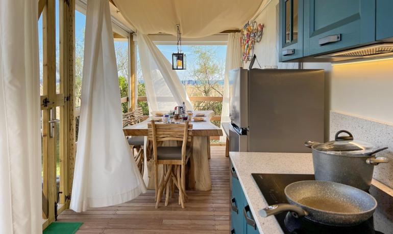 Cucina all'aperto con tavolo in legno e vista sul giardino.